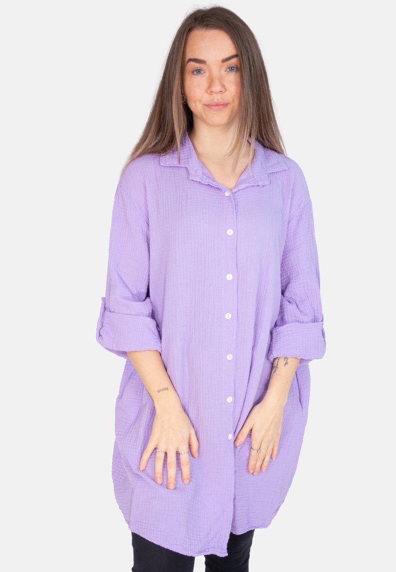 Lavendelfarbenes, übergroßes Button-Up-Hemd aus leichtem, strukturiertem Stoff, mit hochrollbaren Ärmeln, abgerundetem Saum, zwei Taschen auf der Vorderseite und weißen Knöpfen.
