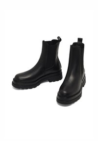 Stivali Chelsea in pelle nera con pannelli elastici laterali, punta rotonda e suola spessa e robusta. Include una linguetta sul retro.
