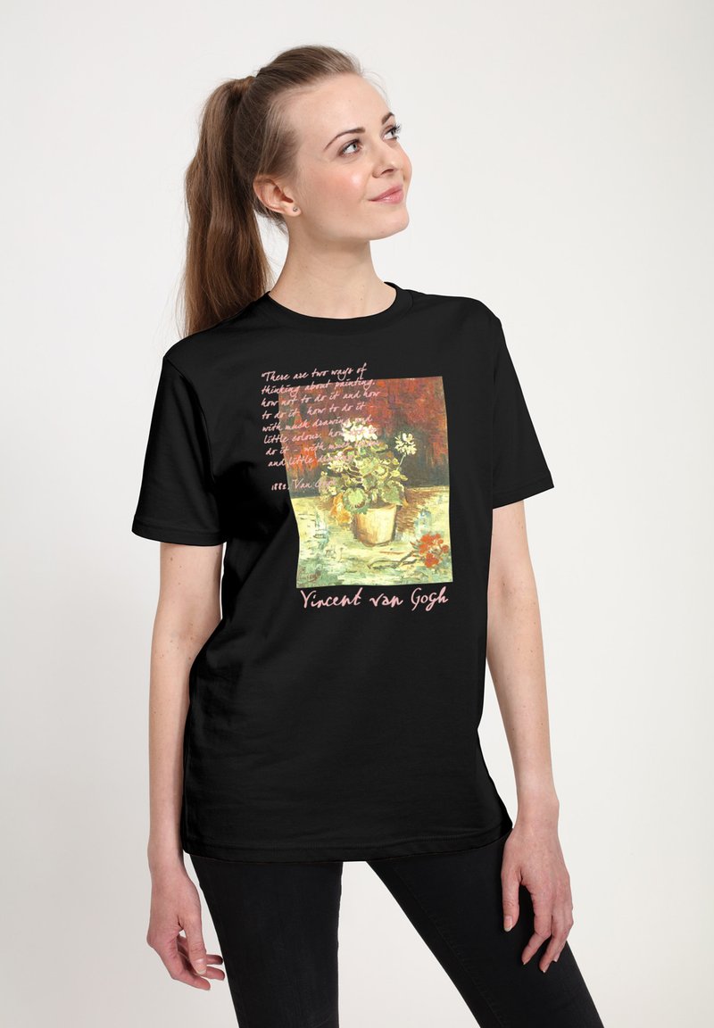 Young woman in black shirt with Vincent van Gogh floral painting and quote printed on front, looking up and smiling slightly.