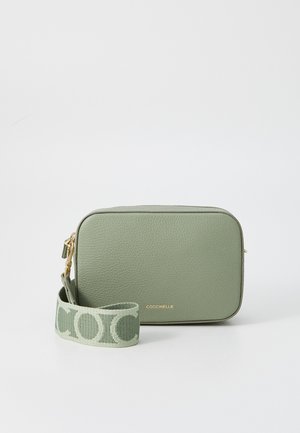 Green leather crossbody bag with a rectangular shape. Features a gold zipper and a fabric strap with a logo pattern. Smooth texture.
