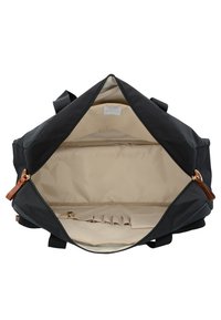 Borsa da viaggio nera in tessuto con interno beige, dotata di chiusura con zip, dettagli in pelle e numerose tasche interne per l'organizzazione.