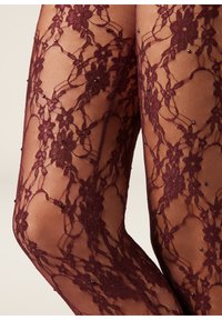 Primo piano di gambe che indossano calze a rete bordeaux trasparenti decorate con piccoli perline nere.