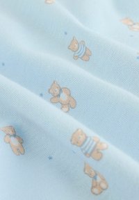 Lyseblåt stof med en blød tekstur, der har et gentaget mønster af små tøjdyr iført stribede dragter.