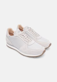 Hellgraue Sneakers aus einer Kombination von Wildleder und Mesh-Materialien, mit Schnürdesign, abgerundetem Zehenbereich und Gummisohle mit strukturiertem Profil.
