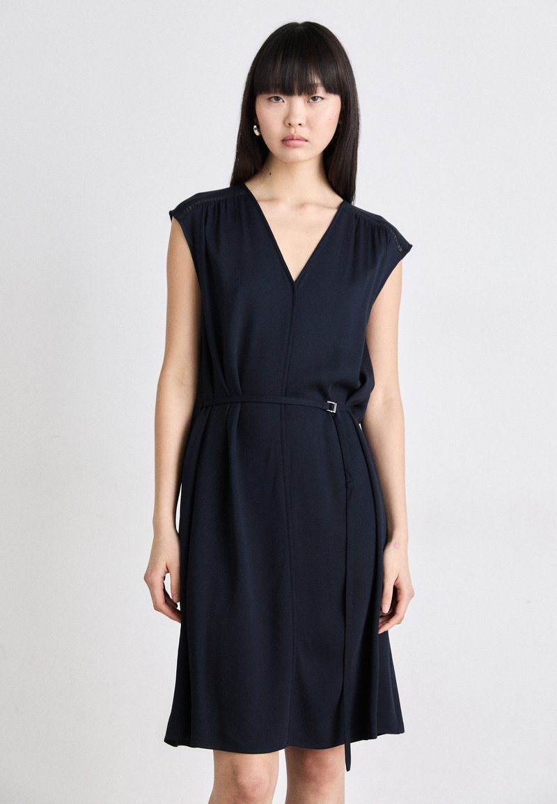 Navy blue dress with a V-neckline, short sleeves, and a cinched waist featuring a metal buckle. Smooth, lightweight fabric with minimal detailing.