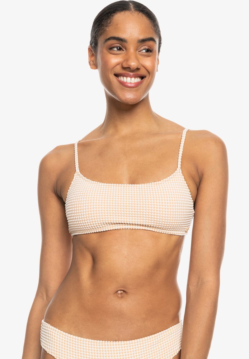 Gingham-patroon bikini top in perzik en roomkleur, met dunne schouderbandjes en een cropped ontwerp. Textuurdetail van de stof zichtbaar.