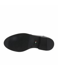 Sole di scarpa in pelle nera con gomma testurizzata e scanalature orizzontali, un tacco leggero e taglia contrassegnata come 37 vicino all'area del tallone.