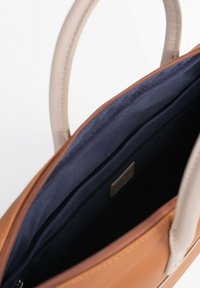 Bruine en beige leren tote bag met gestructureerd ontwerp, voorzien van een donkerblauwe binnenkant en een ritszak voor organisatie.