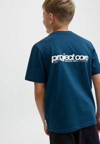 Tamno plava pamučna majica kratkih rukava s bijelim natpisom na leđima koji glasi "project core CREATIVE DEPT." i logotipom.