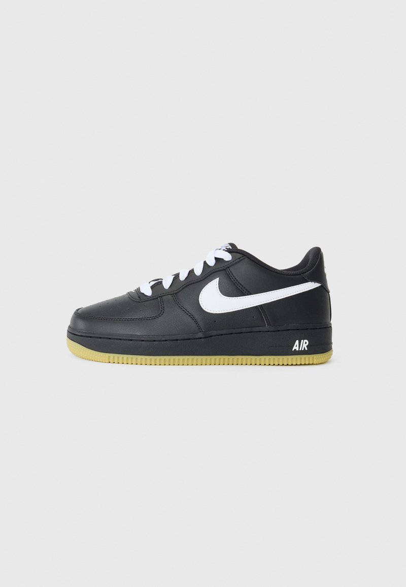 Must värvi nahast tennis鞋,valge swoosh, paeltega disain, kummist tald kollaste aktsentidega ja "AIR" bränding kannal.