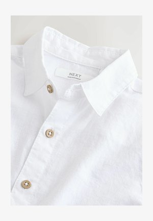 Valge linane särk, millel on klassikaline krae, puidust nupud ja brändi silt. Kangal on pehme tekstuur ja õrn läige.