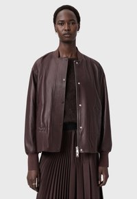 Burgundská kožená bomber bunda s žebrovanými detaily, stříbrnými doplňky a bočními kapsami, zkombinovaná s skládací tmavě hnědou sukní.