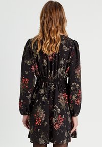 Black floral dress with long sleeves, gathered waist, and a flared skirt. Features colorful flower and butterfly patterns in red, green, and gold.