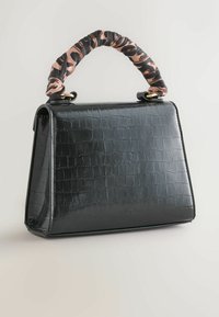 Sac à main noir en cuir à motif crocodile avec une conception structurée, poignée douce en tissu enroulé rose et noir, mettant en avant des accents en métal doré.