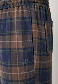 Pantalones de lounge de cuadros en colores marrón, azul marino y verde. Cintura elástica con bolsillo lateral. Logo "JP 1880" en la tela. Textura suave.