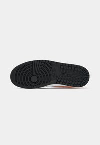 Nike-Sneaker-Sohle aus strukturiertem schwarzem Gummi mit kreisförmigem Muster und integriertem Branding, entworfen für Grip und Langlebigkeit.