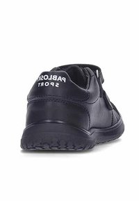 Zapato deportivo negro de cuero con una suela texturizada y una correa ajustable tipo gancho y lazo. Presenta un logo blanco en la parte posterior.