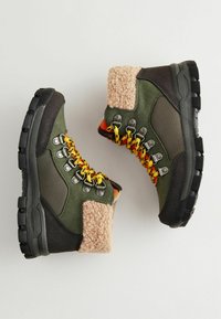 Wysokie buty trekkingowe do kostki w ciemnozielonym i czarnym kolorze, z miękkim beżowym kołnierzem i wielokolorowymi sznurowadłami, z metalowymi oczkami oraz teksturowaną podeszwą.