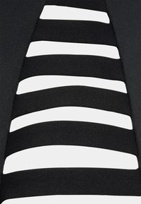 Black fabric with white horizontal stripes, featuring a snug fit and smooth texture, creating a layered design with contrasting colors.