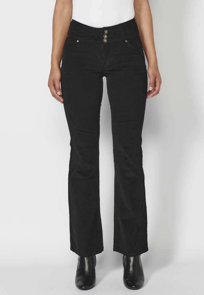 Jeans de campana negros con una cintura alta, que cuentan con tres botones metálicos y bolsillos frontales. Fabricados en denim con una textura suave.