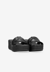 Sandalias de plataforma negras hechas de material sintético suave, con correas cruzadas y una suela tejida texturizada.