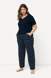 Námořnické tričko s krátkým rukávem a vlnkovaným výstřihem spárované s pruhovanými pyžamovými kalhotami s modro-bílými vodorovnými pruhy. Oba kousky jsou ležérní móda.