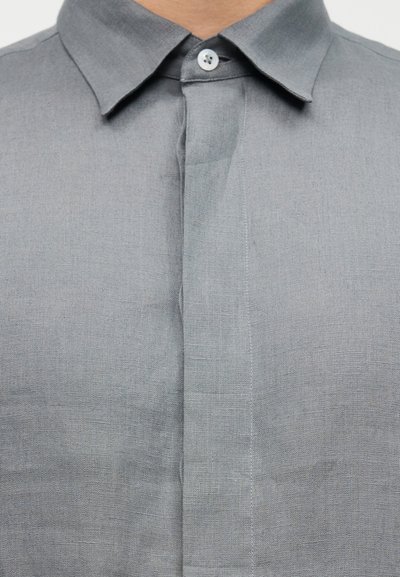 Γκρι πουκάμισο από λινό με κλασικό γιακά, κούμπωμα με κουμπιά μπροστά και υφασμάτινη υφή. Καθαρές γραμμές και ραμμένη εφαρμογή.