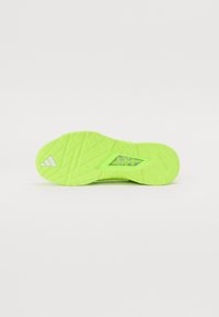 Bright neon green athletic shoe sole with textured pattern and cut-out details. Features logo and "TRAXION" branding. Rubber material.