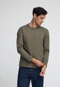 Olivgrön långärmad T-shirt i bomullsblandning, rund hals, figursydd design med en diskret logotyp på bröstet, slät textur.