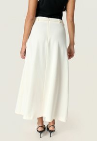 Gonna maxi bianca e fluida con una texture morbida e zip nascosta. Presenta una vita ben rifinita e delicate pieghe per il movimento.