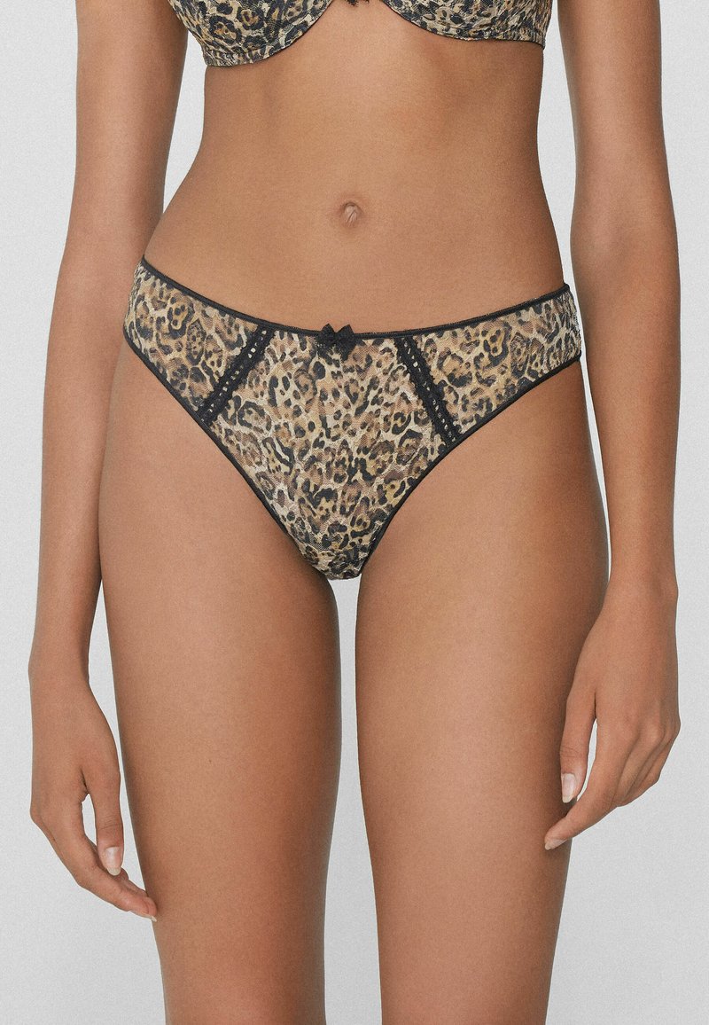 String léopard avec une bordure en dentelle, des accents noirs et un petit nœud à l'avant. Fabriqué en tissu léger.
