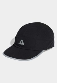 Gorra negra hecha de tela sintética con corona redondeada, visera plana y acentos plateados reflectantes. Presenta un logo de tres rayas blancas en la parte frontal.