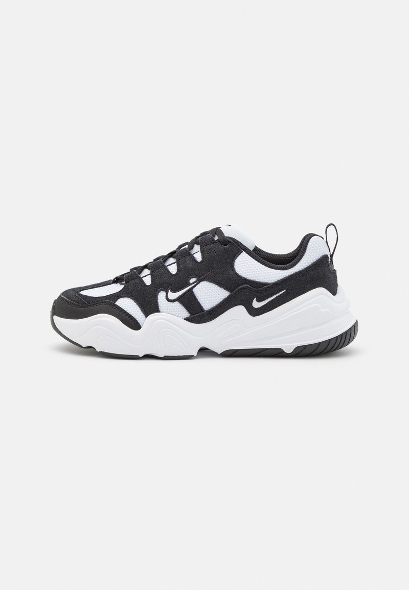 Chaussure de sport noire et blanche présentant un mélange de matériaux en maille et en daim, une épaisse semelle blanche et une semelle extérieure noire texturée avec des accents de marque.