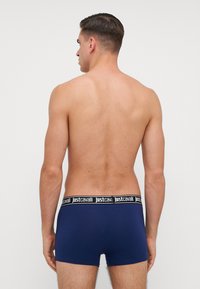 Boxeri navy dintr-un material elastic negru, cu logo-ul "justcavalli". Materialul pare să fie neted și ajustat, cu un design de înălțime medie.