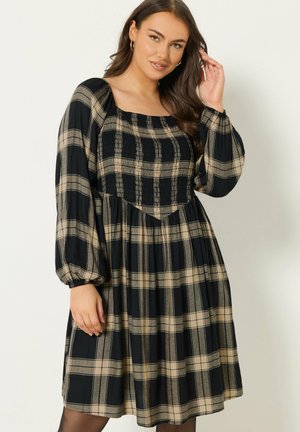 Vestido a cuadros en negro y beige con escote cuadrado, cuerpo fruncido y mangas abullonadas; hecho de tela ligera.