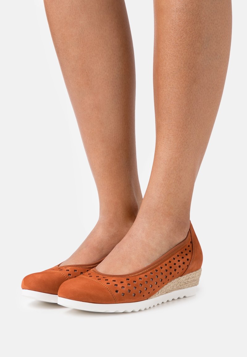 Chaussures compensées en daim orange avec design perforé, bout arrondi et semelle en caoutchouc blanche. Dotées d'une semelle intermédiaire enveloppée de jute pour la texture.