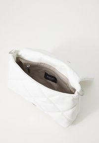 Borsa bianca in ecopelle trapuntata con chiusura a zip, dotata di una fodera beige e di una tasca interna visibile. Etichetta JOOP! Jeans all'interno.
