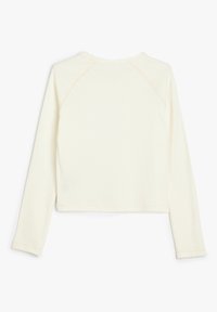 Krämfärgad långärmad topp med rund halsringning, tillverkad av ribbat tyg. Har raglanärmar och en rak nederkant. Slät textur.