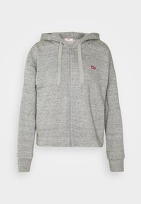 Sweat à capuche gris clair zippé avec cordons de serrage et petit logo Levi's rouge sur le côté gauche de la poitrine, présenté sur fond blanc.