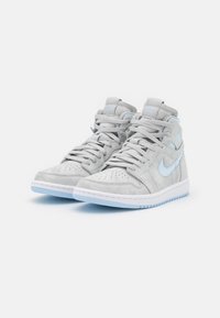 Zapatillas altas en ante gris claro con puntera perforada, acentos en azul claro, cordones redondos y una suela intermedia blanca con suela de goma.