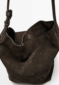 Brun ruskinds bucket-style taske med en snoet læderrem og en snaplukning, der har en blød tekstur og en rund form.