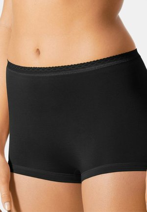 Mustat, saumatonta kangasta olevat shortsit, joissa on pehmeä tekstuuri ja aallotettu elastinen vyötärö. Ne ovat lähellä vartaloa istuvat ja pituudeltaan reiden puoliväliin saakka.