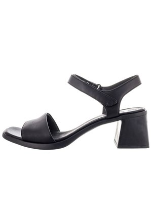 Sandale noire à talons avec bout ouvert, design de sangle incurvée, sangle de cheville et un talon carré épais. Texture lisse semblable au cuir.