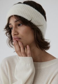 Biały dziany opaska wykonana z miękkiego materiału, z prążkowaną fakturą. Noszona z jasnokremowym, oversize'owym swetrem.