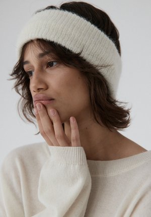 Biały dziany opaska wykonana z miękkiego materiału, z prążkowaną fakturą. Noszona z jasnokremowym, oversize'owym swetrem.