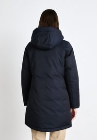 Mørkeblå isolert parkas med hette, med rett snitt og synlige sømmer, som går til midten av låret med en glatt tekstur.