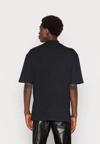 Black short-sleeve t-shirt with a relaxed fit, crew neck, and smooth cotton texture. Minimalist design with no visible patterns or accents.
