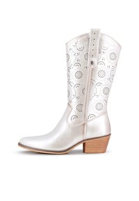 Bota de vaquero metálica plateada con patrones de corte floral, punta afilada y tacón de madera apilada. Presenta una correa con múltiples agujeros de ajuste.