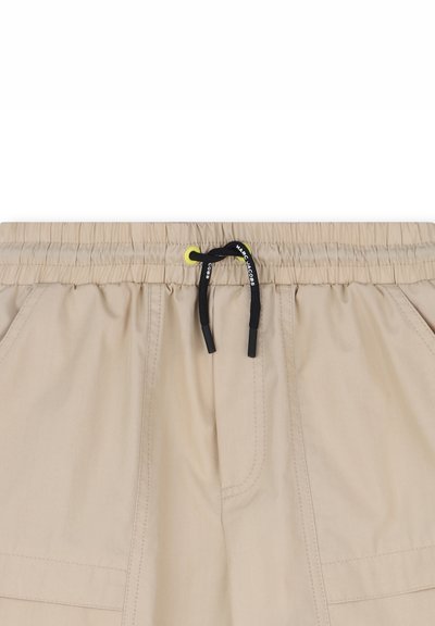 Pantaloncini beige con vita elasticizzata, coulisse nera con scritta bianca "MARC JACOBS" e tasche a toppa laterali.