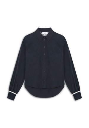 Camisa de botón azul marino hecha de tela suave, con cuello, dos bolsillos frontales y detalles en blanco en los puños de las mangas.